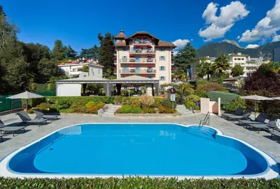 a large blue swimming pool in front of a building at Hapimag Apartments Meran in Merano