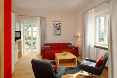 a living room with a red couch and chairs at Hapimag Apartments Meran in Merano