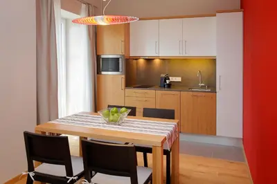 a kitchen with a wooden table with chairs and a dining room at Hapimag Apartments Meran in Merano