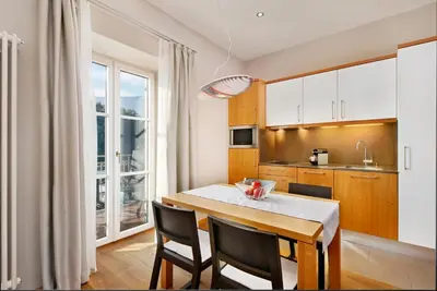a kitchen with a table and chairs and a kitchen with a window at Hapimag Apartments Meran in Merano