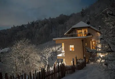 a house with a fence in the snow at night at Firmelein in Appiano sulla Strada del Vino