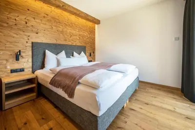 a bedroom with a large bed and a wooden wall at MULIN Appartements in Valles