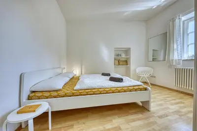 a white bedroom with a bed and a chair at HOMESTWENTY3 - Home four in Caldaro