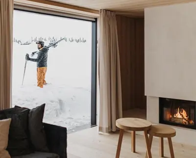 a man standing in the snow with skis on a window at Larix Lodge in La Villa