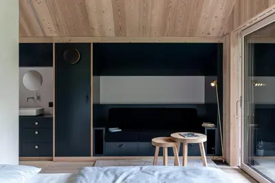 a bedroom with black walls and a bed and two stools at Larix Lodge in La Villa