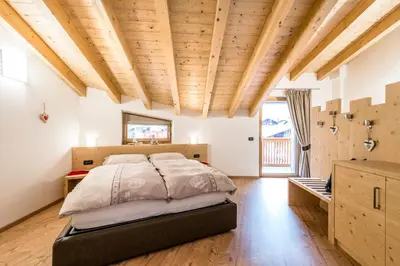 a bedroom with a bed and a wooden ceiling at Cèsa Baissa in Campitello di Fassa