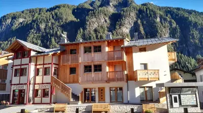 a building with a mountain in the background at Cèsa Baissa in Campitello di Fassa