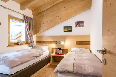 a bedroom with two beds and a window at Cèsa Baissa in Campitello di Fassa