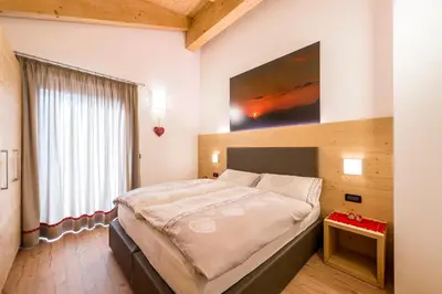 a bedroom with a large bed with a painting on the wall at Cèsa Baissa in Campitello di Fassa