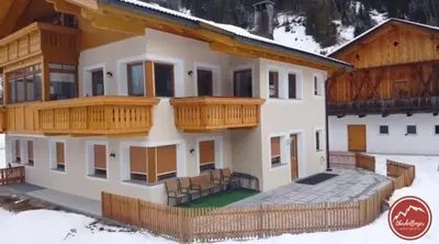 a house with wooden balconies in the snow at Apartments Oberhollenzer in Braies