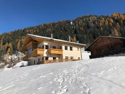 a house in the snow with footprints in the snow at Apartments Oberhollenzer in Braies