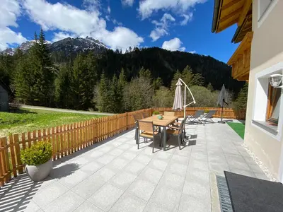 a patio with a wooden fence and a table and chairs at Apartments Oberhollenzer in Braies