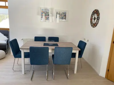 a dining room table with blue chairs and a clock at Apartments Oberhollenzer in Braies
