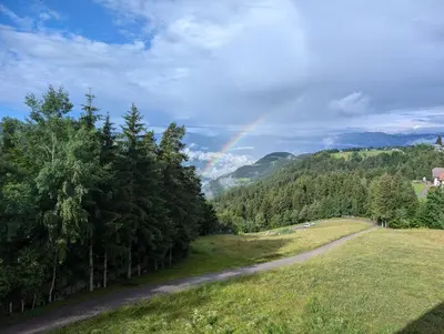 a rainbow in the sky over a field with a road at Vidora Apartments in Soprabolzano
