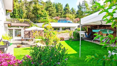 a garden with a white tent and a house at Vidora Apartments in Soprabolzano