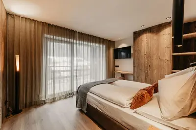 a bedroom with a large bed and a large window at Dolomites Chalet Niuasi in Ortisei