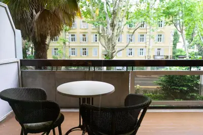 a table and chairs on a balcony with a view of a building at Meran/o Centro Guest House in Merano