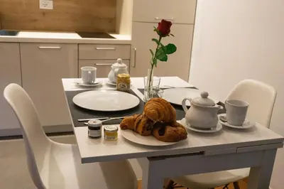 a table with a plate of croissants and a flower at Meran/o Centro Guest House in Merano