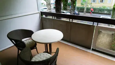 a balcony with a table and chairs and a window at Meran/o Centro Guest House in Merano