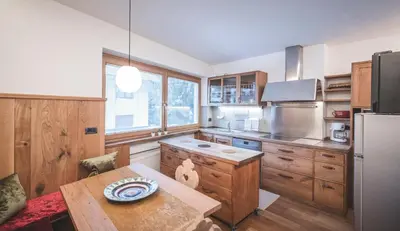 a kitchen with wooden cabinets and a table and a refrigerator at Dolce Vita Apartment in Valdaora