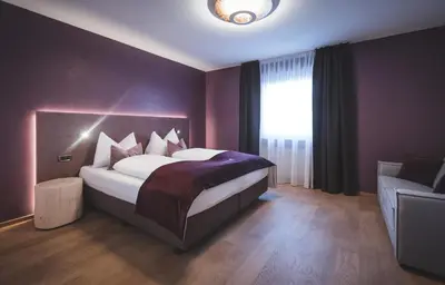 a bedroom with a large bed in a purple room at Dolce Vita Apartment in Valdaora