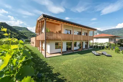 a house with a large yard with two benches at Ferienwohnungen Ortsried in Nalles