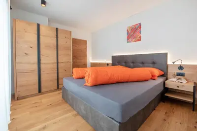 a bedroom with a bed with an orange pillow on it at Ferienwohnungen Ortsried in Nalles