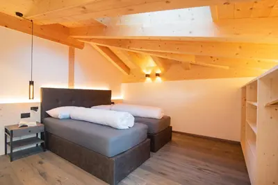 two beds in a room with wooden ceilings at Ferienwohnungen Ortsried in Nalles