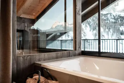 a bath tub in a room with a large window at Surega - Idyllic Farmhouse in San Cassiano