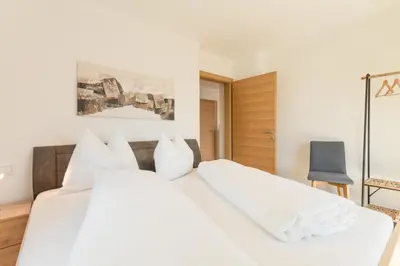 a bedroom with two white beds and a blue chair at Apartment La Brunella in Laion