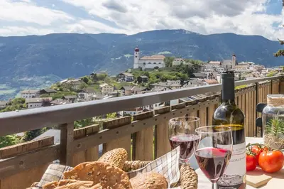 a table with glasses of wine and bread on a balcony at Apartment La Brunella in Laion