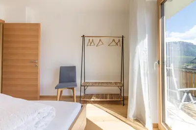 a bedroom with a bed and a chair and a window at Apartment La Brunella in Laion