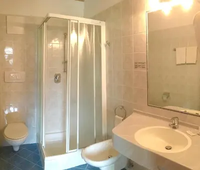 a bathroom with a shower and a toilet and a sink at Hotel Turmwirt in Ora/Auer