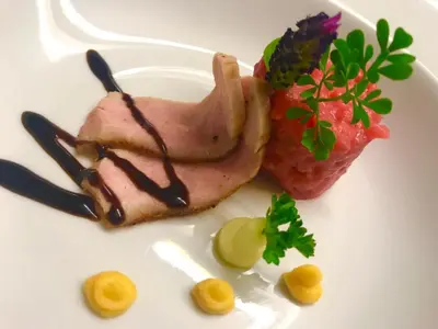 a white plate with a piece of meat and a strawberry at Hotel Turmwirt in Ora/Auer