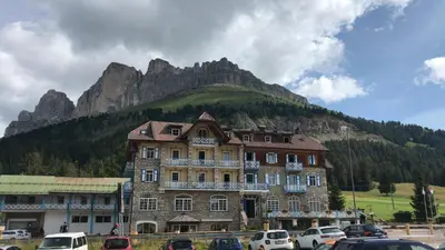 a large building in front of a mountain at SUITE25 GOLFHOTEL in Carezza al Lago