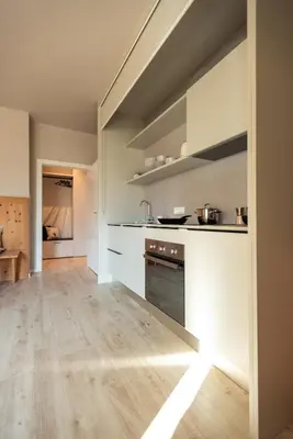 a kitchen with white cabinets and a wooden floor at Avista Apartments Sky in Merano