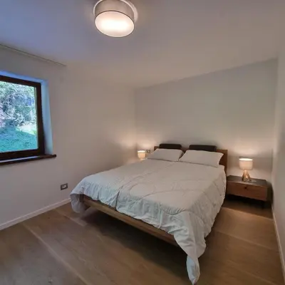 a white bedroom with a bed and a window at Casa Tura San Vigilio in San Vigilio Di Marebbe