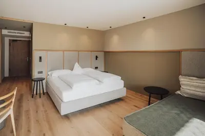 a bedroom with a white bed and a couch at Hotel Lisetta in Tirolo