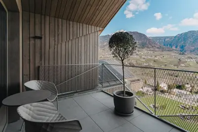 a balcony with a table and a potted tree at Hotel Lisetta in Tirolo