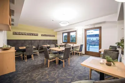 a dining room with tables and chairs and windows at Apparthotel Feldhof - Living and Bistro in Nova Ponente