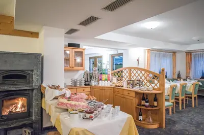 a kitchen with a fireplace and a table with food at Apparthotel Feldhof - Living and Bistro in Nova Ponente