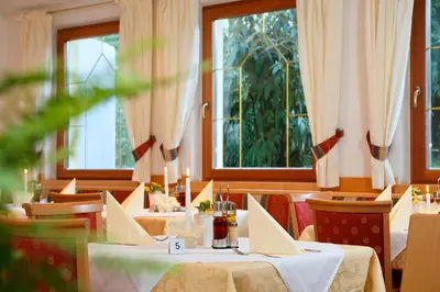 a restaurant with tables and chairs and windows at Hotel Unterrain in Appiano sulla Strada del Vino