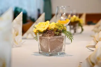 a vase filled with yellow roses sitting on a table at Hotel Unterrain in Appiano sulla Strada del Vino