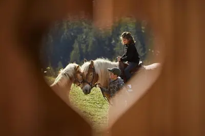 a boy and a girl riding on a horse at Sotciastel Antico Chalet in Badia