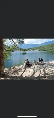a group of people sitting on the shore of a lake at Azalea in Cornaiano