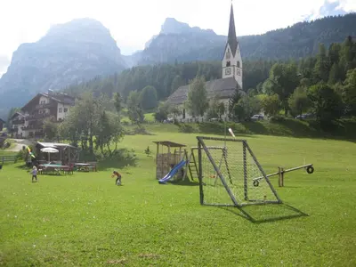 a group of children playing in a field with a church at Garni Miriam in La Villa