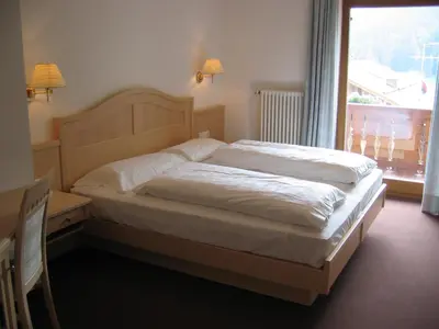 a bed in a bedroom with a large window at Garni Miriam in La Villa