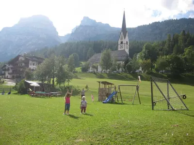 a group of children playing in a field with a church at Garni Miriam in La Villa