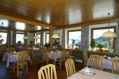 a dining room with tables and chairs and windows at Garni Miriam in La Villa