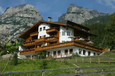 a building on a hill with mountains in the background at Garni Miriam in La Villa